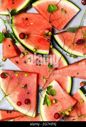Stapel von frisch geschnittenen Wassermelonen und Walderdbeeren mit grünen Blättern. Gesundes Lebensmittelkonzept. Draufsicht. Stockfoto