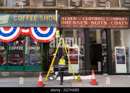 Glasgow, Schottland, Großbritannien. 14. Juli 2021. Die Dreharbeiten für den neuesten Film von Indiana Jones beginnen vor Ort im Stadtzentrum von Glasgow. Die Dreharbeiten fanden in der Cochrane Street statt, und an den Ladenfronten in der St Vincent Street wurden letzte Feinheiten vorgenommen, um sie in amerikanische Geschäfte der Zeit umzuwandeln. Iain Masterton/Alamy Live Nachrichten. Stockfoto