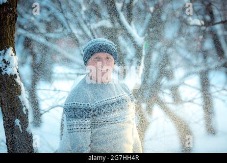 Porträt eines Mannes an einem verschneiten Tag im Wald. Der Typ in Wintersportbekleidung. Stockfoto