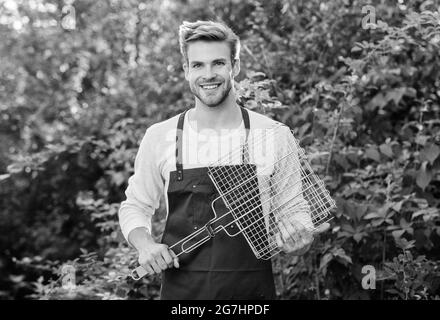 Picknick-Konzept. Gesunde Mahlzeit. Rezeptgrill. Verschiedene Methoden Grillfleisch Huhn Gemüse und Meeresfrüchte. Mann hält das Gitter. Speisen werden zum Essen serviert Stockfoto