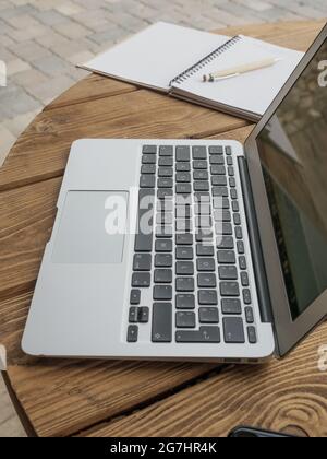 Offener Laptop auf Holztisch im Freien. Home Office-Konzept. Seitenansicht. Stockfoto