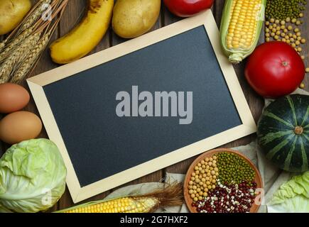 Frisches Bio-Gemüse, Obst, Eier, Bohnen und Hühneraugen mit Tafel auf einem Holztisch Stockfoto