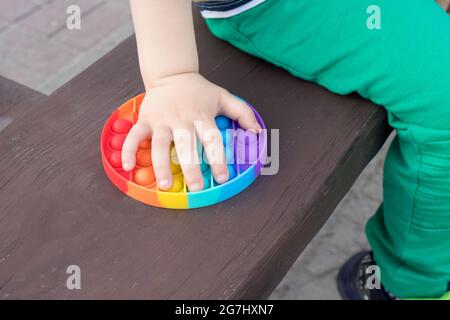 Spielzeug Antistress bunt Pop it und ein kleines Kind Nahaufnahme. Stockfoto