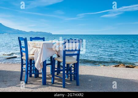 Blaue Stühle und Tisch in einer typisch griechischen Taverne in der Nähe des Meeres in Kissamos. Kreta, Griechenland Stockfoto