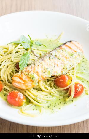 Spaghetti Pesto Lachs in weißem Teller auf Holztisch Stockfoto