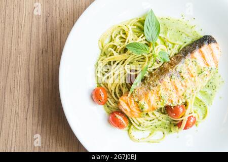 Spaghetti Pesto Lachs in weißem Teller auf Holztisch Stockfoto