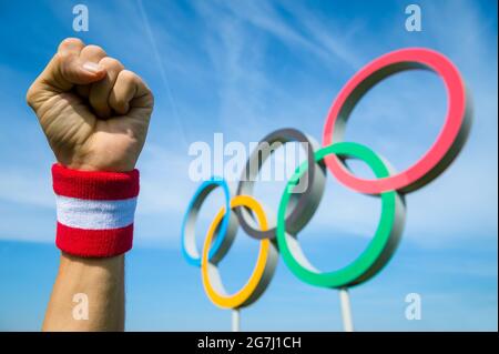 RIO DE JANEIRO - CA. MAI 2016: Japanischer Athlet mit rot-weißem Armband schlägt mit der Faust vor den Olympischen Ringen in die Luft Stockfoto