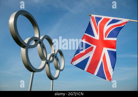 RIO DE JANEIRO - MÄRZ 2016: Die Union Jack-Flagge hängt vor einem großen Satz glänzender metallischer olympischer Ringe unter hellblauem Himmel. Stockfoto