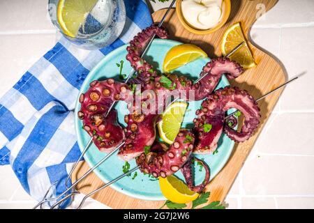 Meeresfrüchte-Kebabs, Oktopus auf Spießen mit Zitrone, Sauce und Kräutern. Diät gesundes Picknick-Konzept, auf Kachel Sommer sonnigen Hintergrund oben Viiew Kopie Platz Stockfoto