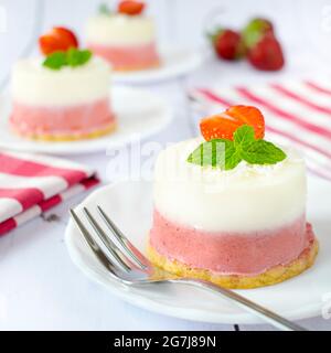 Mini-Kokos- und Erdbeerkäsekuchen. Monoportionen von Sommerdessert mit Kokosnuss, weißer Schokolade und frischen Erdbeeren. Stockfoto