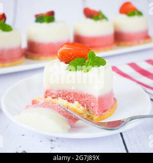 Mini-Kokos- und Erdbeerkäsekuchen. Monoportionen von Sommerdessert mit Kokosnuss, weißer Schokolade und frischen Erdbeeren. Stockfoto