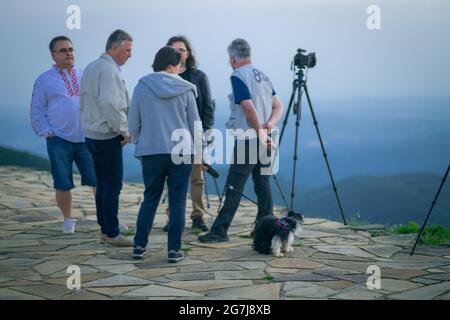 Junge Leute, Fotografen und ein Welpe auf einem Berggipfel erwarten den Sonnenaufgang - July Morning am 01. Juli 2021, Shipka, Bulgarien Stockfoto