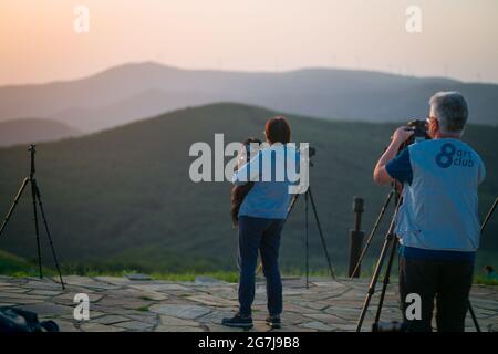 Junge Leute, Fotografen und ein Welpe auf einem Berggipfel erwarten den Sonnenaufgang - July Morning am 01. Juli 2021, Shipka, Bulgarien Stockfoto