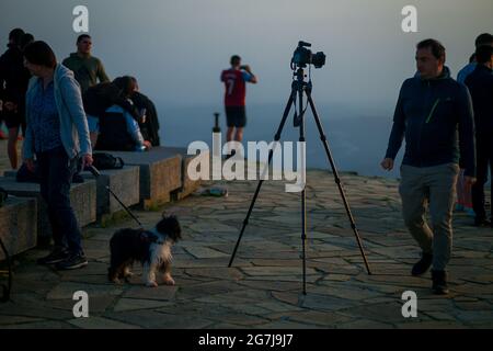 Junge Leute, Fotografen und ein Welpe auf einem Berggipfel erwarten den Sonnenaufgang - July Morning am 01. Juli 2021 Stockfoto