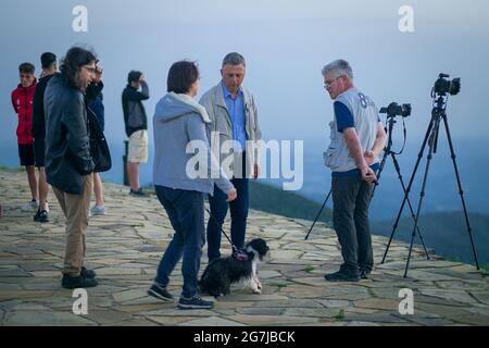 Junge Leute, Fotografen und ein Welpe auf einem Berggipfel erwarten den Sonnenaufgang - July Morning am 01. Juli 2021 Stockfoto