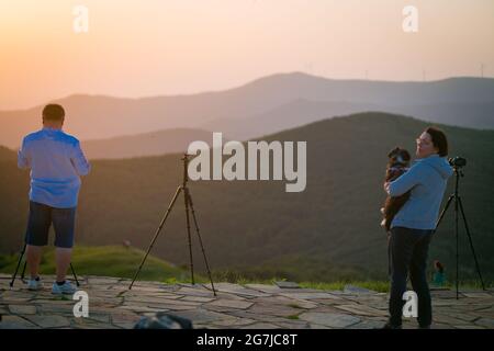 Junge Leute, Fotografen und ein Welpe auf einem Berggipfel erwarten den Sonnenaufgang - July Morning am 01. Juli 2021, Shipka, Bulgarien Stockfoto