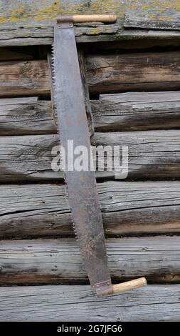 Sah zweihändig vor dem Hintergrund einer Blockwand Stockfoto