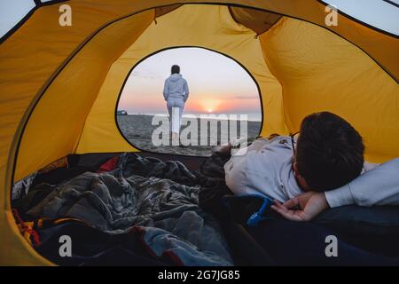 Paar schlafen im Zelt Blick auf Sonnenaufgang. Wanderkonzept. Strand Stockfoto