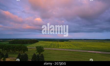 Blau-lila Himmel mit Wolken über grünem Feld Stockfoto