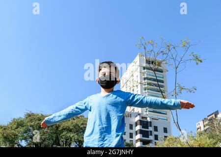 8-jähriges Kind mit offenen Armen an einem sonnigen Tag im öffentlichen Park. Stockfoto