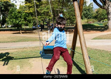 8-jähriges Kind, das an einem sonnigen Tag von einer Schaukel springt. Stockfoto