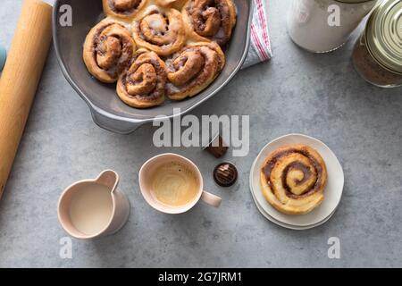 Süßes Frühstück mit einer Tasse Kaffee, Milch und hausgemachten leckeren Zimtschnecken. Keine Leute in der Nähe. Stockfoto