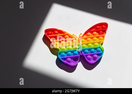 Regenbogenschmetterling. LGBT-Flaggensymbol-Konzept, Stolz, Liebe und Einheit. Kinderspielzeug Pop IT oder Simple Dimple in Form eines Regenbogenschmetterlings Stockfoto