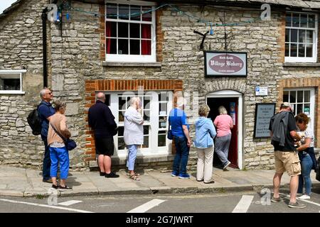 Corfe Castle, Dorset, England - 2021. Juni: Besucher, die sich vor der Dorfbäckerei anstellen. Stockfoto