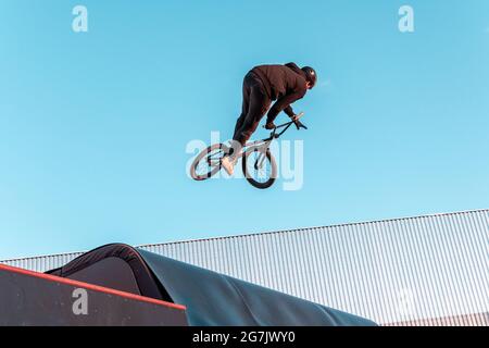 BMX-Fahrer macht Trick auf Rampe im Skatepark. Sport, Extremsport, Freestyle, das Konzept der Outdoor-Aktivität. Stockfoto