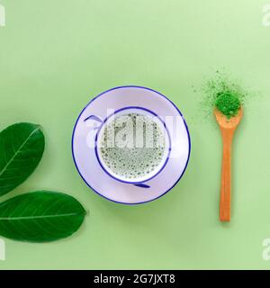 Grüner Matcha-Tee in einer weißen Tasse, Teepulver in Holzlöffel, Draufsicht. Gesundes Getränk. Flach liegend. Stockfoto
