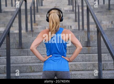 Rückansicht einer Sportlerin mit Kopfhörern, die im Freien für das Training in der Stadt steht Stockfoto