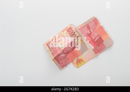 Konzeptfoto Rupiah Papiergeld, zerrissen oder zerbrochen 100000, Flat Lay auf weißem Hintergrund Stockfoto