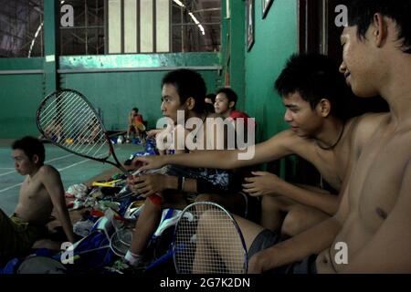 Junge Badminton-Athleten ruhen sich nach dem Training aus, da einer von ihnen einen Tennisschläger hält, der für Schattenbadminton verwendet wird, im Badminton-Club Jaya Raya in Jakarta, Indonesien. Stockfoto