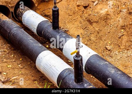 Installation der Verteilungseinheit des Heiz- und Wasserversorgungsnetzes. Rahmen für die Verbindung von Rohren im Erdgraben. Stockfoto