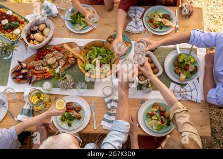 Gruppe von Menschen toasten mit Gläsern frisches Wasser über den Tisch mit leckeren gesunden Lebensmitteln Stockfoto