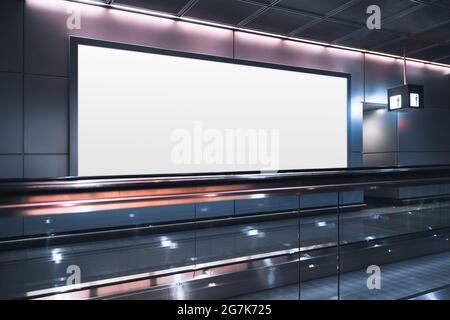 Eine riesige rechteckige leere Plakatwand neben dem Travelator in einem modernen Abflugbereich des Flughafens; eine weiße leere Plakatvorlage im Inneren eines Terminals o Stockfoto