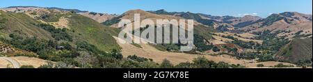 Cambria, CA, USA - 9. Juni 2021: Panoramalandschaft von Back Country mit trockenem Ranchland und grünen Bäumen an steilen Flanken von Bergen unter Stockfoto