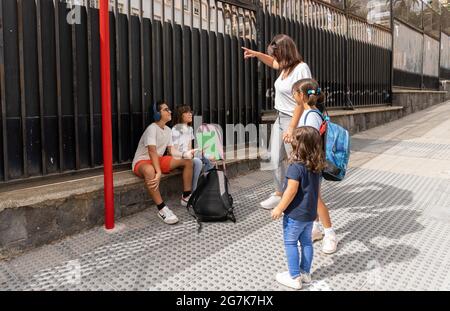 Kaukasische Schulkameraden warten an der Schulbushaltestelle Stockfoto