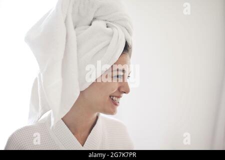 Porträt einer jungen lächelnden Frau in einer Robe mit in ein Handtuch gewickelten Haaren Stockfoto