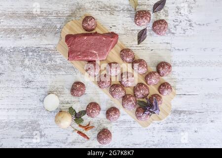 Schuss von frischen rohen Fleischbällchen auf einem Holzbrett mit Zutaten Stockfoto