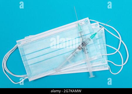 Impfungs-, Immunologie- oder Reimpfungskonzept - zwei medizinische Spritze und die medizinische Maske liegen auf blauem Tisch in der Arztpraxis in einem Krankenhaus oder einer Klinik Stockfoto