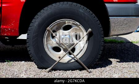 Ein Fahrzeug mit einem flachen Reifen und einem gebrauchsfertigen vier-Wege-Schraubenschlüssel Stockfoto