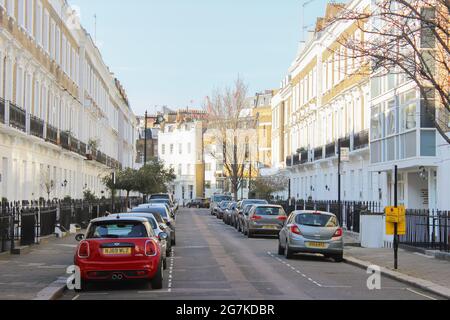 LONDON, VEREINIGTES KÖNIGREICH - 25. Jun 2021: Eine londoner Seitenstraße mit Autos, die auf der Straße geparkt sind Stockfoto