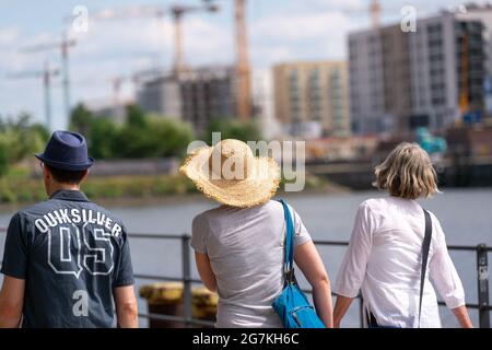 Hamburg, Deutschland. Juli 2021. Kinderwagen mit Sonnenhut laufen über den Versmannkai am Baakenhafen, im Hintergrund sind Kraniche für den Hausbau zu sehen. Quelle: Jonas Walzberg/dpa/Alamy Live News Stockfoto