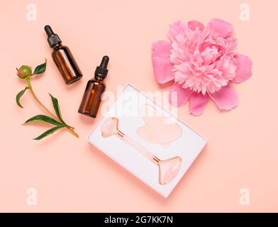 Kosmetische Fläschchen mit ätherischem Öl reinigen weiches Handtuch Rosenquarz Roller Gesichtsmassager Gua-Sha Stein für Gesichtsmassage Stockfoto