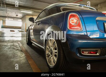 Bangkok, Thailand - 26 Jun 2021 : Nahaufnahme der Rückleuchte oder Heckleuchte, Rad und Tür des Blue Mini cooper auf dem Parkplatz geparkt. Selektiver Fokus. Stockfoto