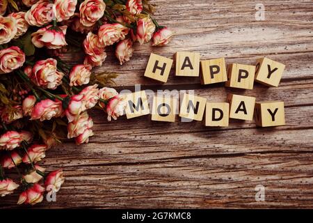 Happy Monday Buchstaben mit Blumendekoration auf hölzernem Hintergrund Stockfoto