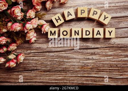 Happy Monday Buchstaben mit Blumendekoration auf hölzernem Hintergrund Stockfoto
