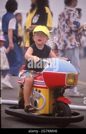 TOKYO, JAPAN - Jul 05, 2021: Kleiner Junge mit gelber Mütze fährt gerne auf einem Vergnügungspark-Motorrad. Stockfoto