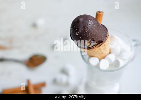 Schokoladeneis in einem Kegel in einem Glas mit Sumpflaibchen auf weißem Hintergrund. Süßes Dessert auf dem Tisch. Zusammensetzung mit Eis Süßer Snack. Stockfoto